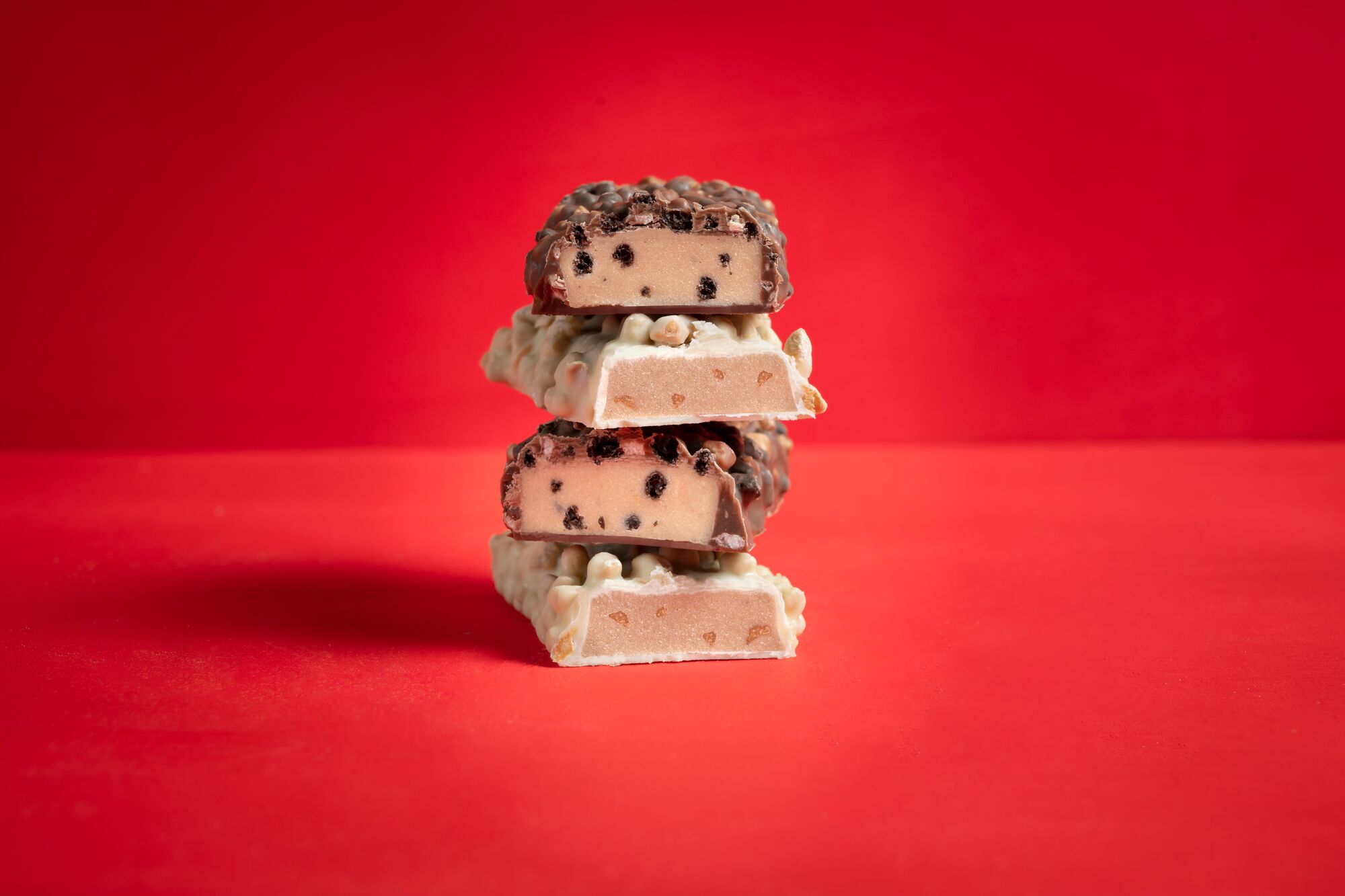 Aufeinander gestapelte Proteinriegel überzogen mit weißer Schokolade und Milchschokolade gefüllt mit Crispies