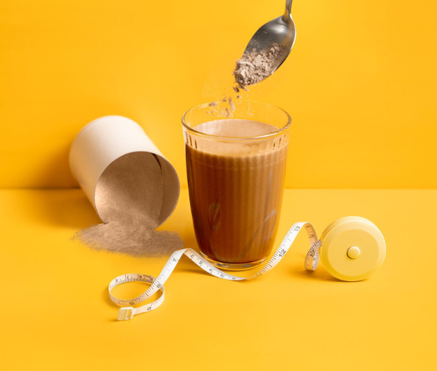 Maßband und Wasserglas mit Schokoladenpulver auf Löffel